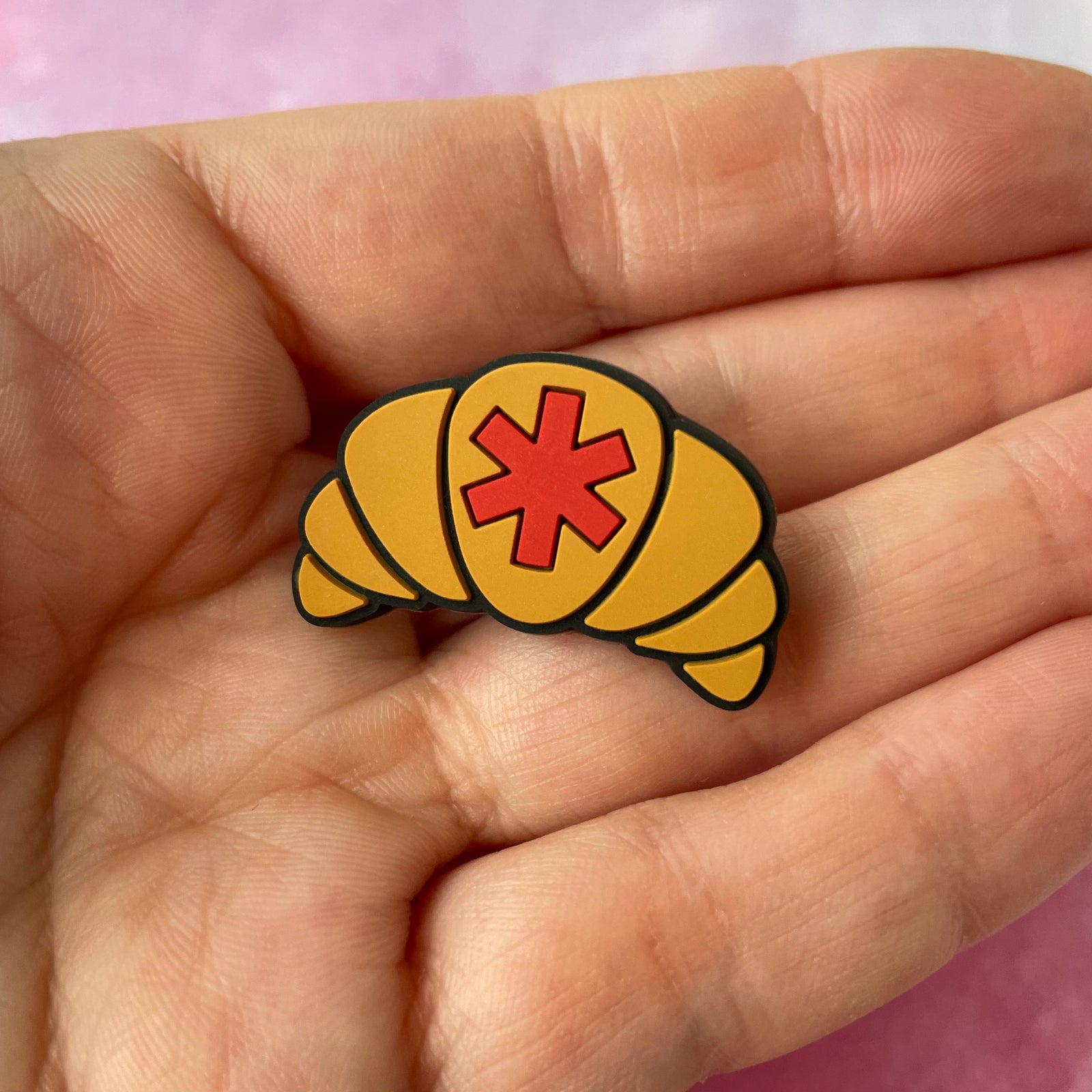 Croissant-shaped pin with a red star on a light gray background