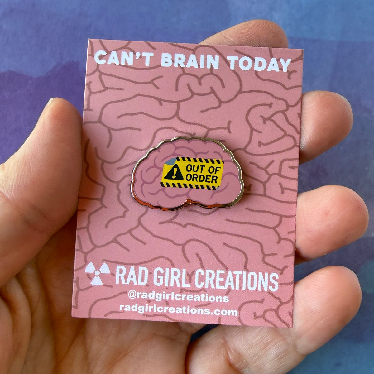 Enamel pin of a pink human brain featuring a yellow 'Out of Order' warning sign with a black exclamation point