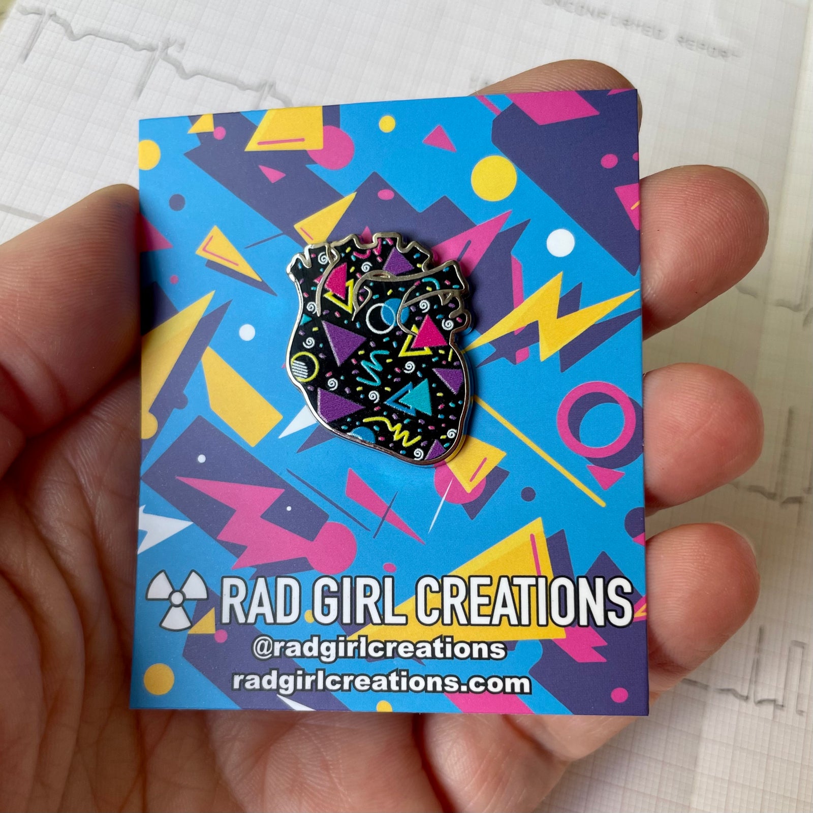 Colorful geometric design heart retro enamel pin on a black background with a gray border