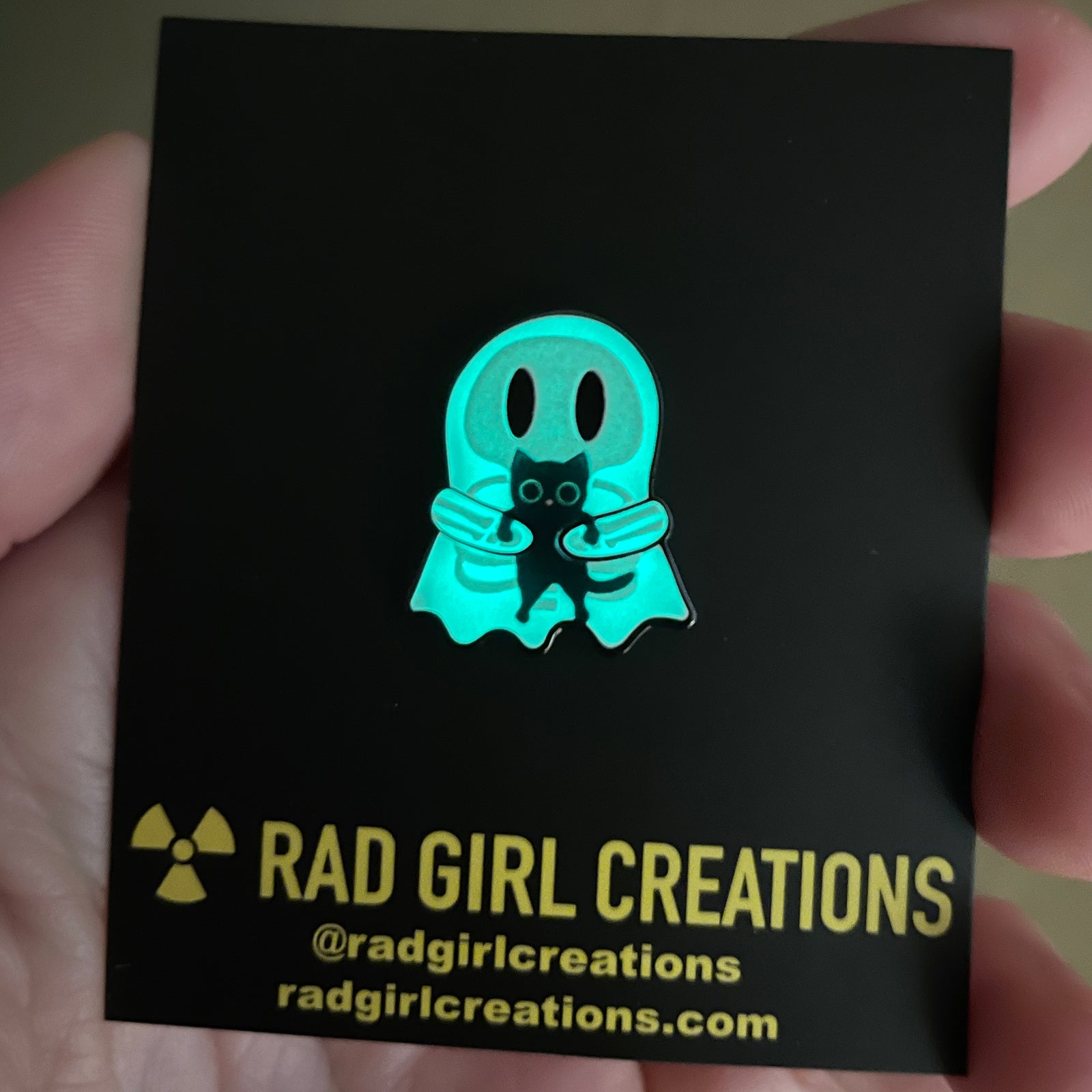 Glowing ghost and black cat pin with 'glows in the dark!' label on a light gray background