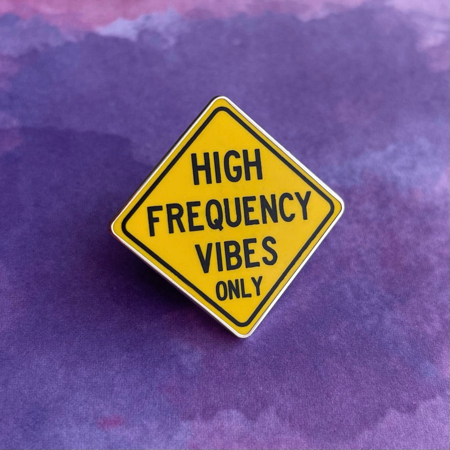 Yellow sign with black text 'HIGH FREQUENCY VIBES ONLY' on a light gray background