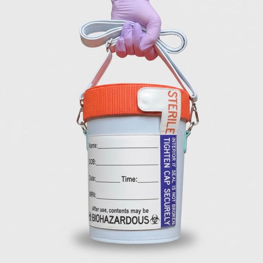 Specimen container shaped bag with orange lid held by a gloved hand on a light gray background