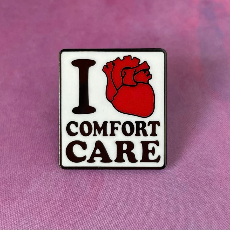 Enamel pin with 'I ❤️ Comfort Care' text on a white background